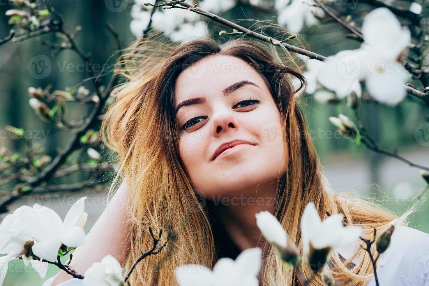 bella ragazza in giardino gode di alberi di magnolia in fiore foto