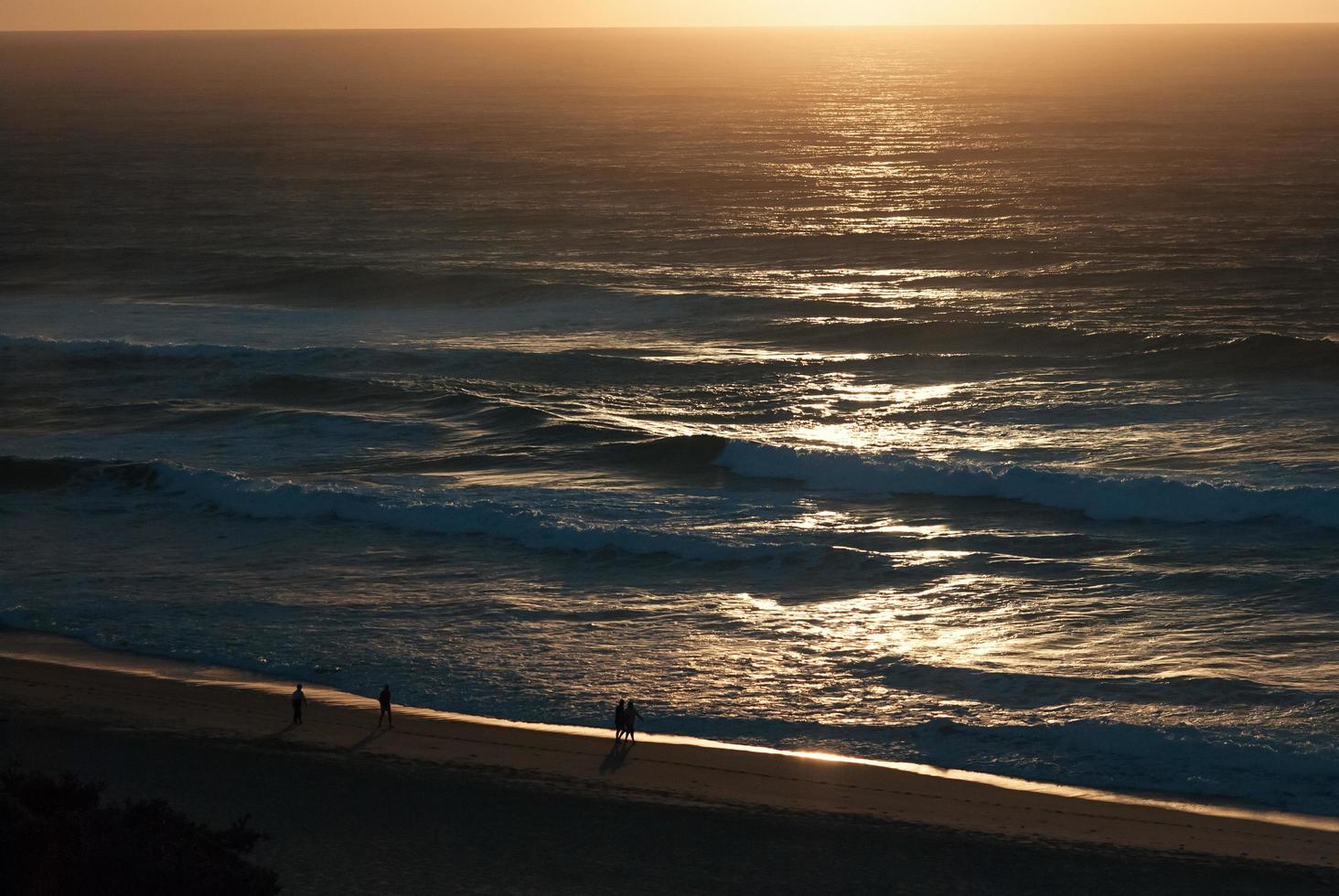 alba presto sulla spiaggia dell'oceano, paesaggio marino, persone di sagome foto