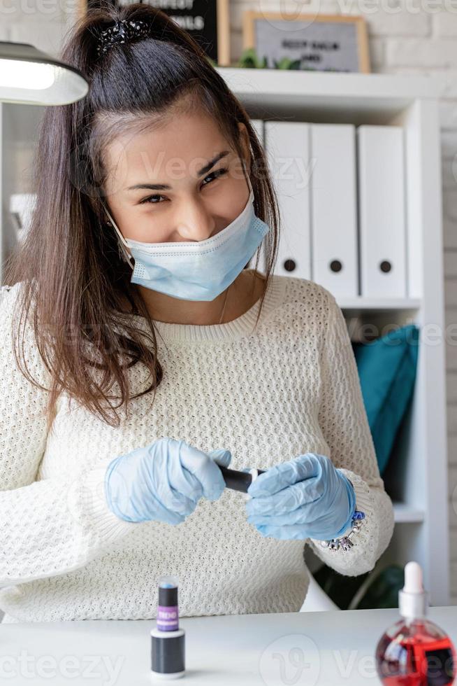 maestro di manicure in maschera e guanti che lavorano nel salone di bellezza foto