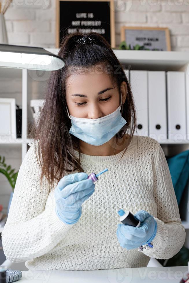 maestro di manicure in maschera e guanti che lavorano nel salone di bellezza foto