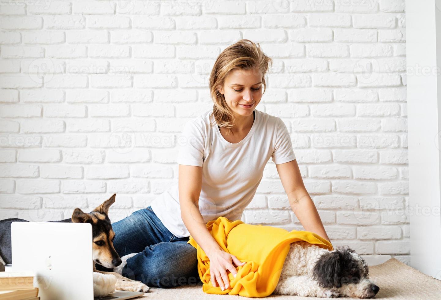 divertente giovane donna in plaid giallo seduta sul pavimento con i suoi cani foto