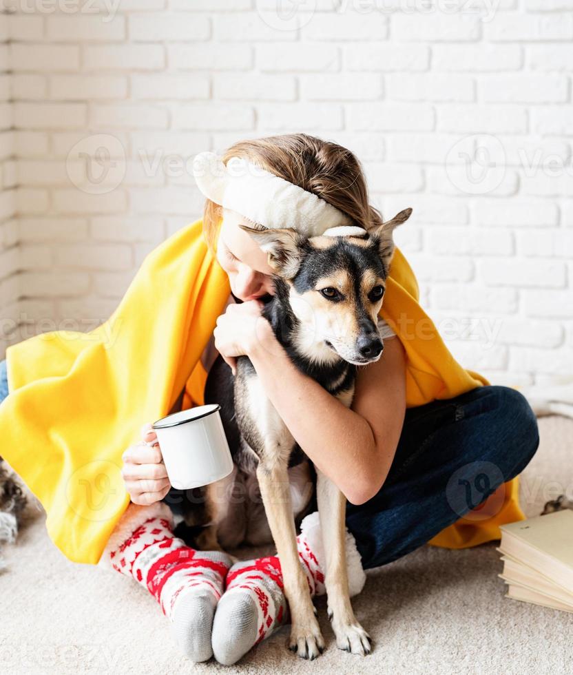 divertente giovane donna in plaid giallo seduta sul pavimento che abbraccia il suo cane foto