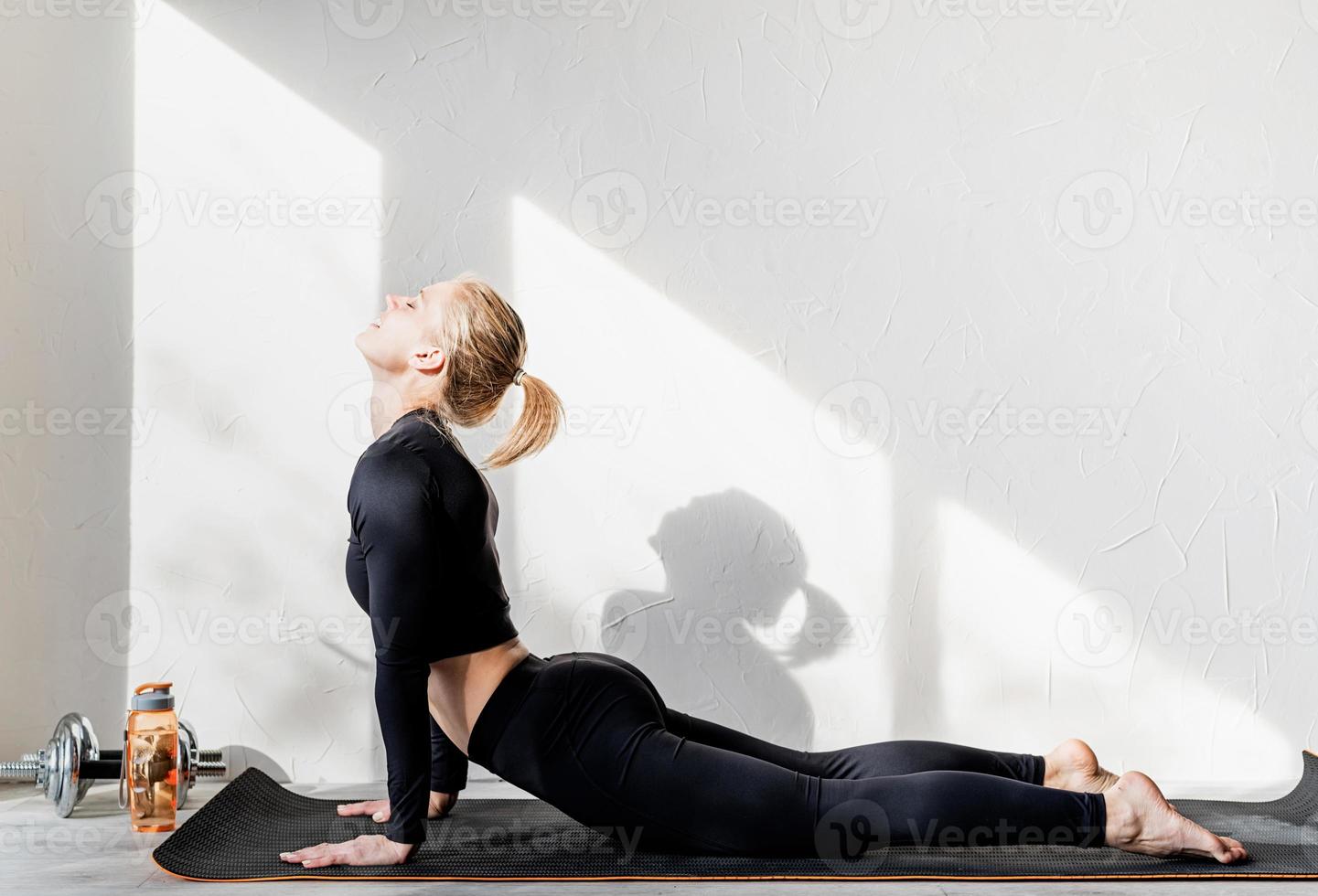 giovane donna atletica che si allena o fa yoga stretching a casa foto