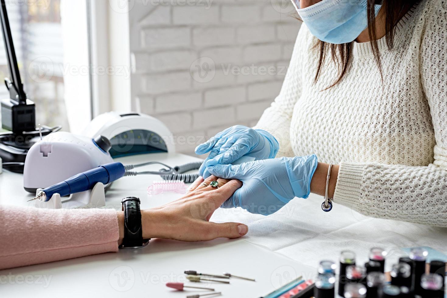 maestro di manicure che pulisce le unghie che fa la manicure a un cliente foto