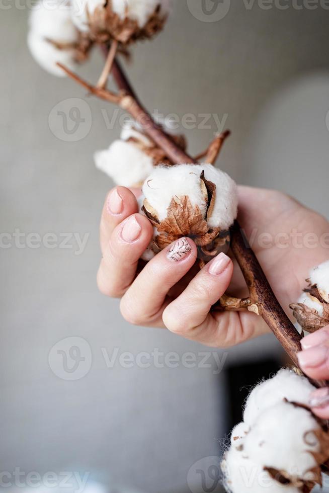 mano femminile con una manicure appena fatta che tiene il cotone foto