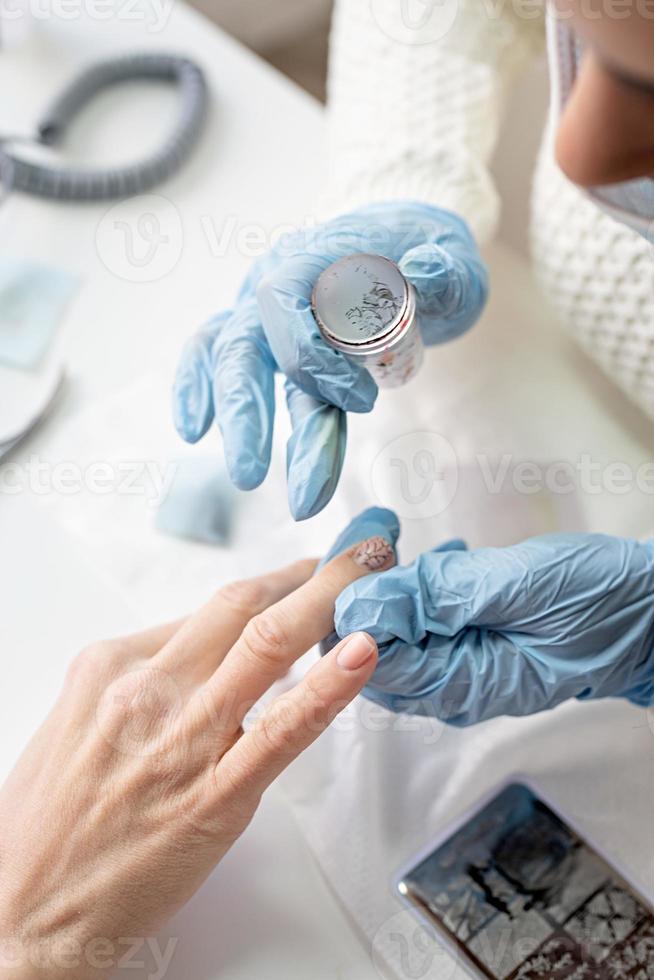 maestro di manicure in maschera e guanti che fa timbratura al cliente foto