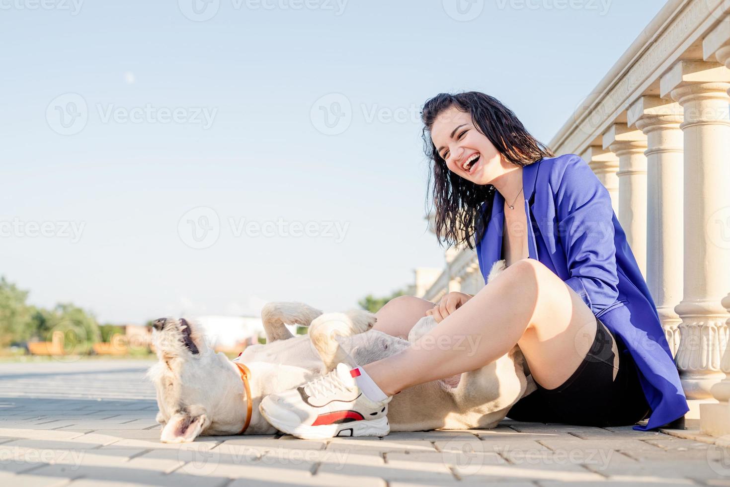 giovane donna allegra che gioca con il suo cane nel parco foto