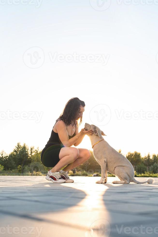 giovane donna attraente che abbraccia il suo cane nel parco? foto