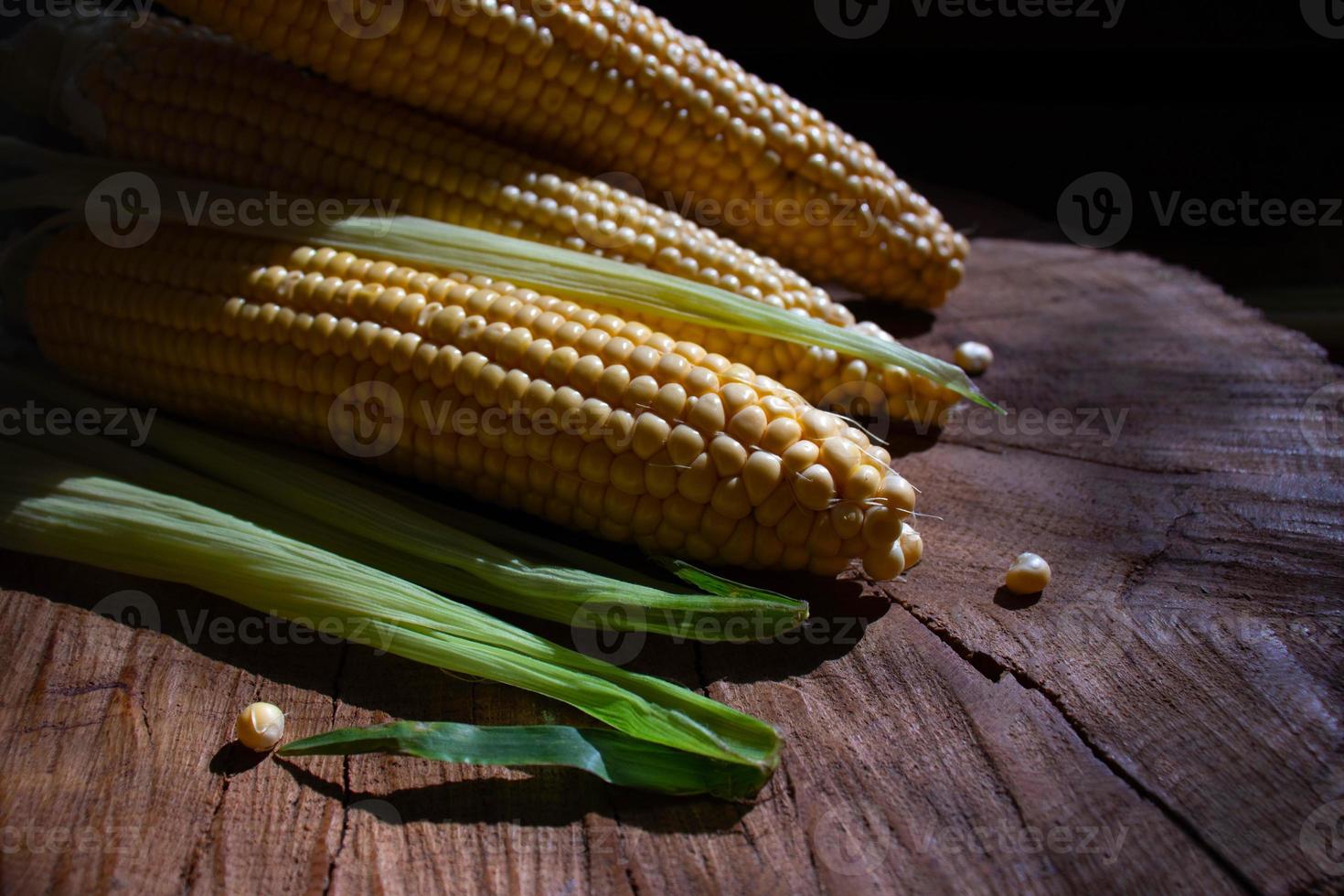 pannocchie di mais con foglie su fondo di legno. cibo di verdure fresche foto