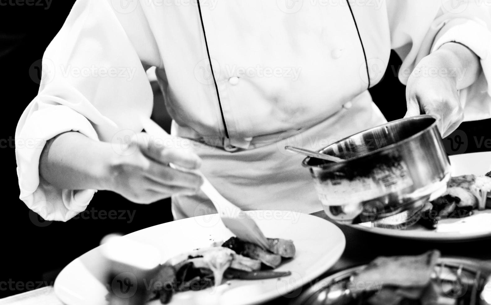 chef che prepara cibo, chef che cucina in una cucina, in bianco e nero foto