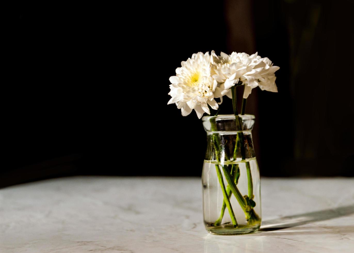 bouquet di fiori bianchi in un vaso su tavola di legno foto