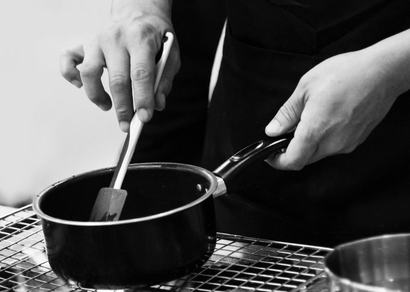 chef che prepara cibo, chef che cucina in una cucina in bianco e nero foto