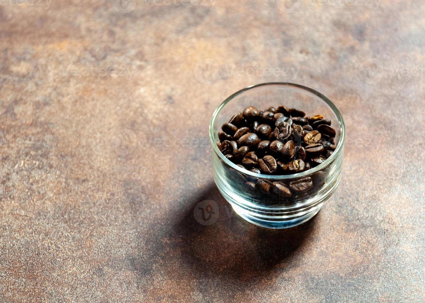 chicchi di caffè freschi in una ciotola di vetro su uno sfondo foto