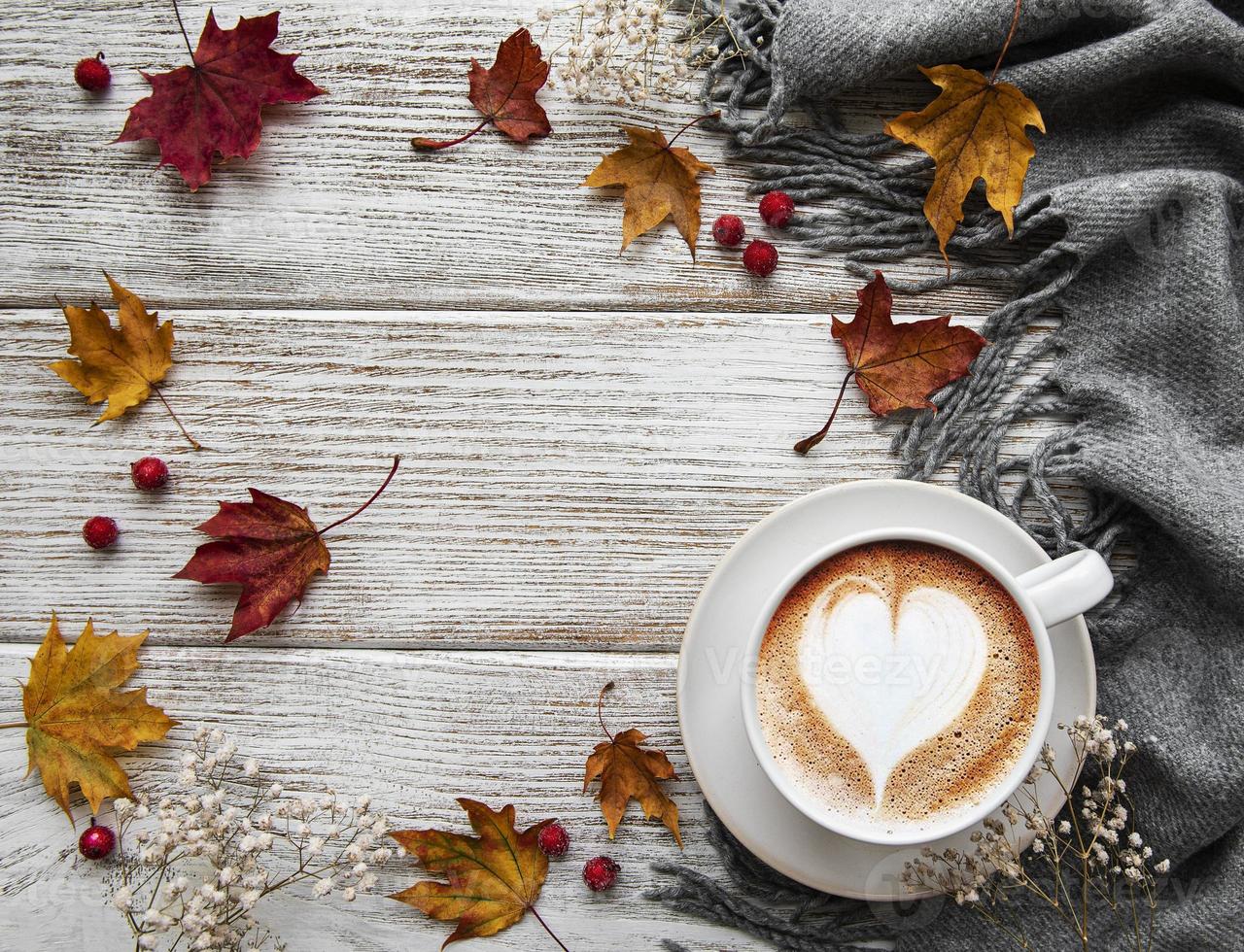 tazza di caffè e foglie secche su fondo di legno bianco foto