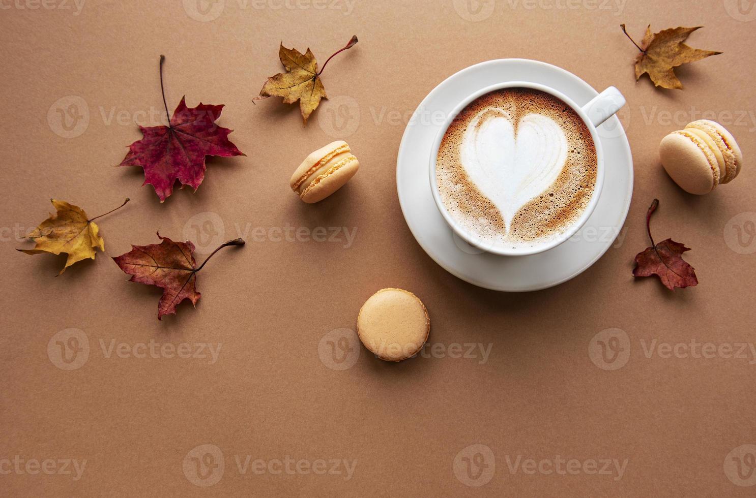 tazza di caffè e foglie secche su sfondo marrone foto