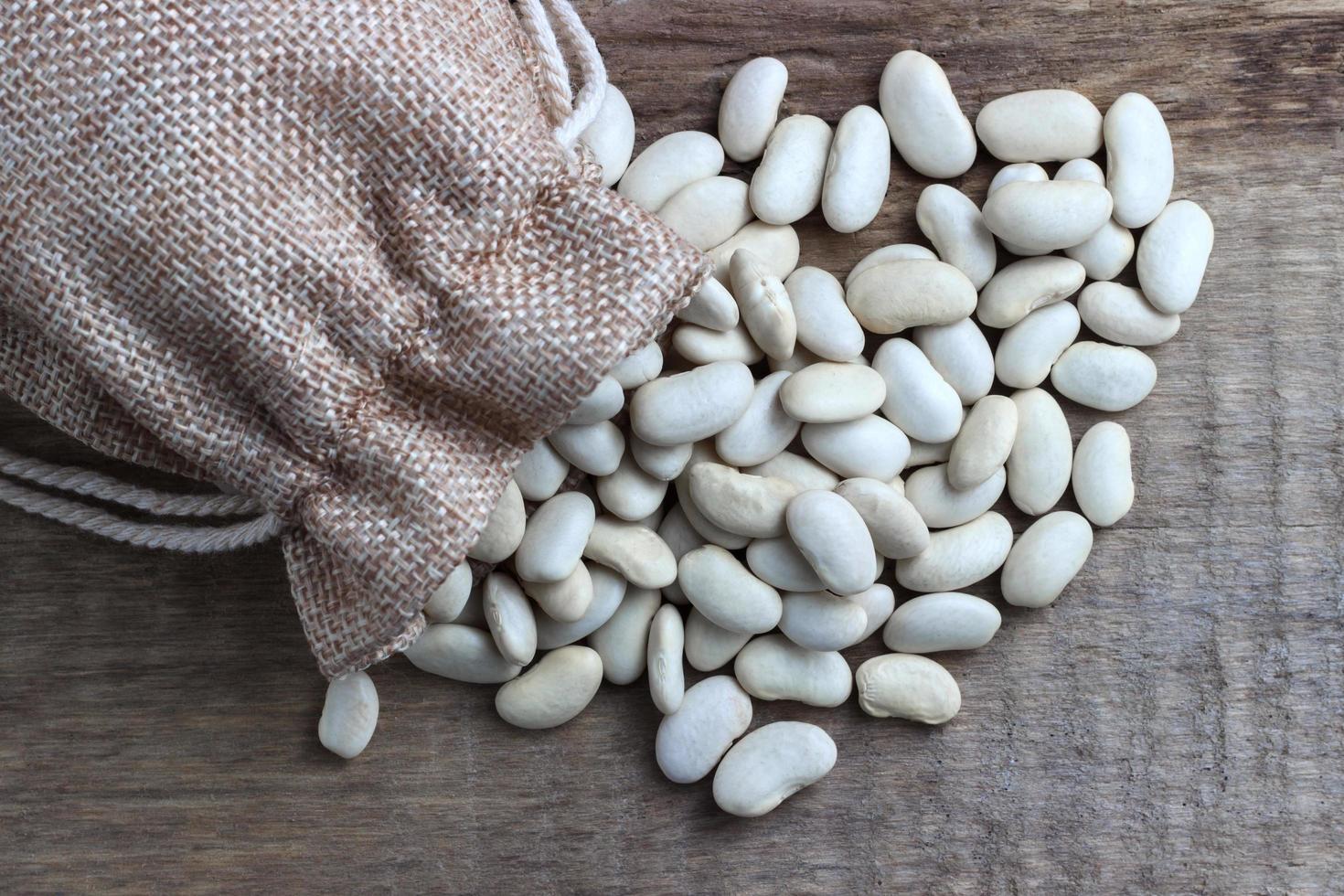 fagioli in un sacchetto su uno sfondo di legno foto