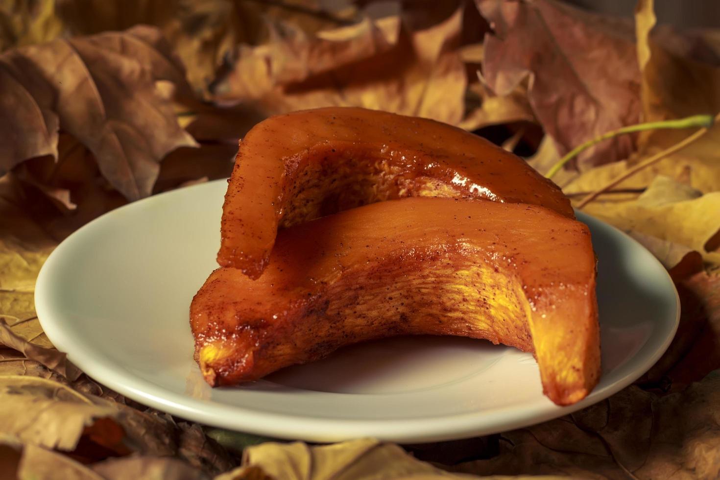 zucca al forno con cannella in un piatto sullo sfondo di foglie foto