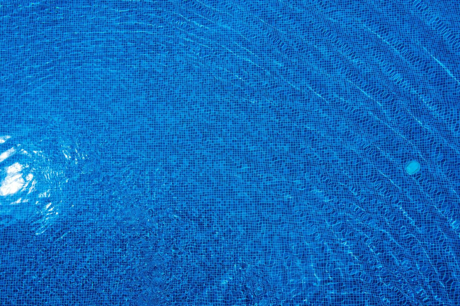leggero riflette via il superficie di il blu nuoto piscina. foto