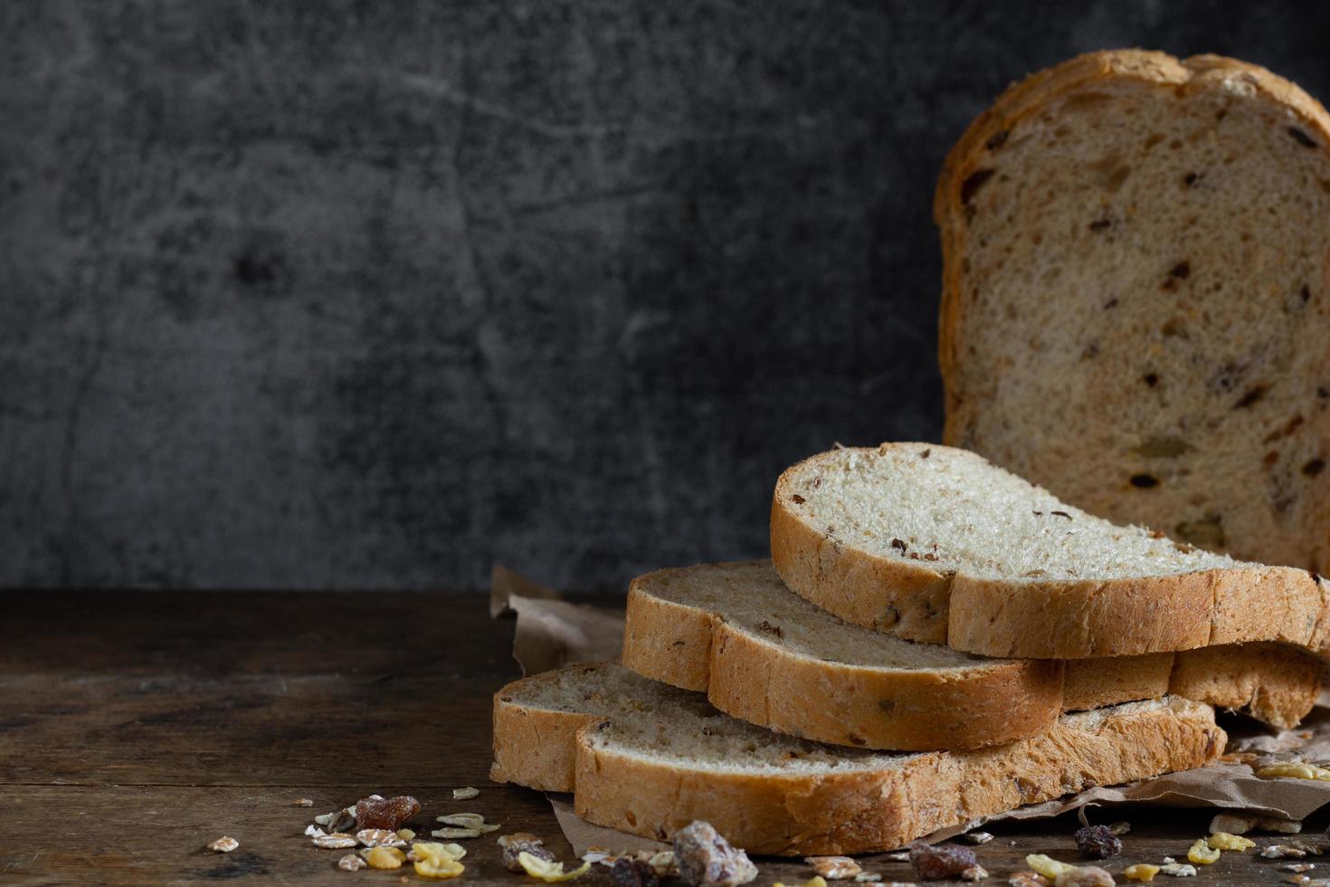 pane integrale di grano affettato su fondo di legno rustico scuro foto