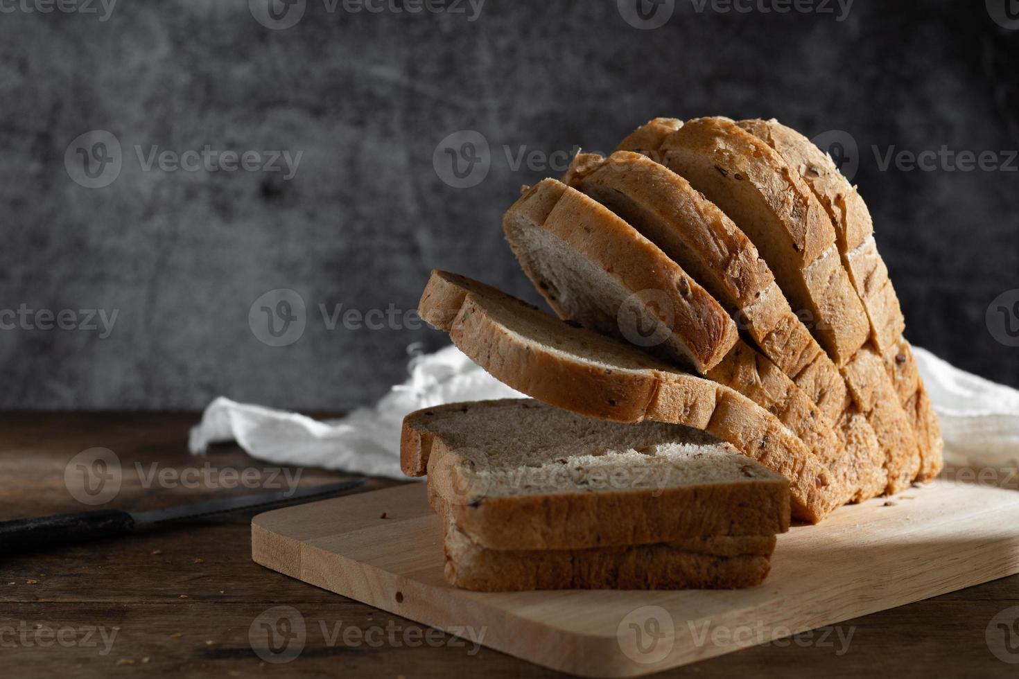 pane integrale di grano affettato su fondo di legno rustico scuro foto