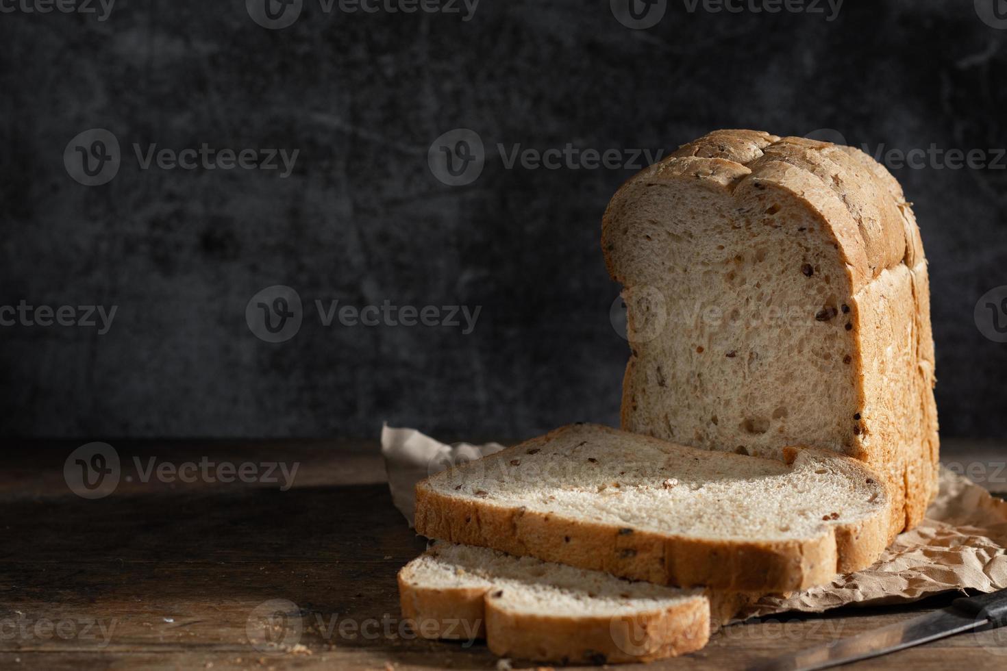 pane integrale di grano affettato su fondo di legno rustico scuro foto