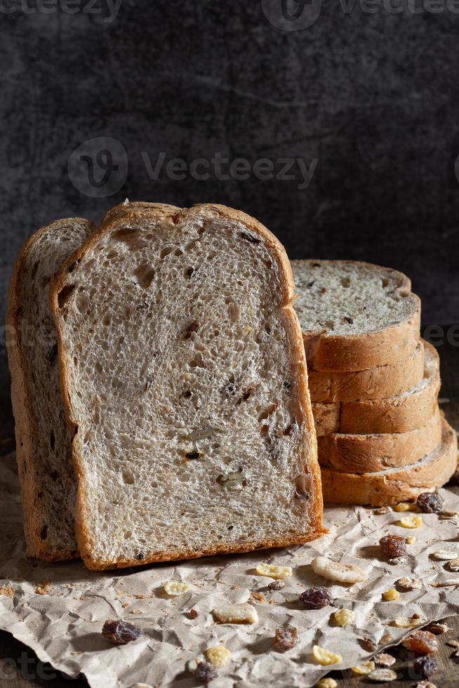 pane integrale di grano affettato su fondo di legno rustico scuro foto