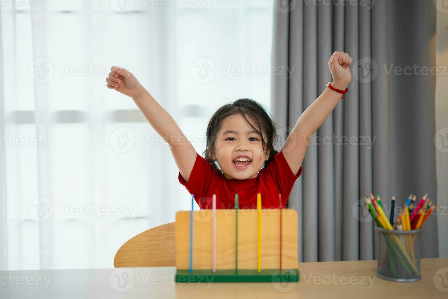 giovane carino asiatico bambino ragazza indossare rosso maglietta è apprendimento il abaco con colorato perline per imparare Come per contare su il tavolo nel il vivente camera a casa. bambino bambino ragazza sviluppo studiando concetto. foto