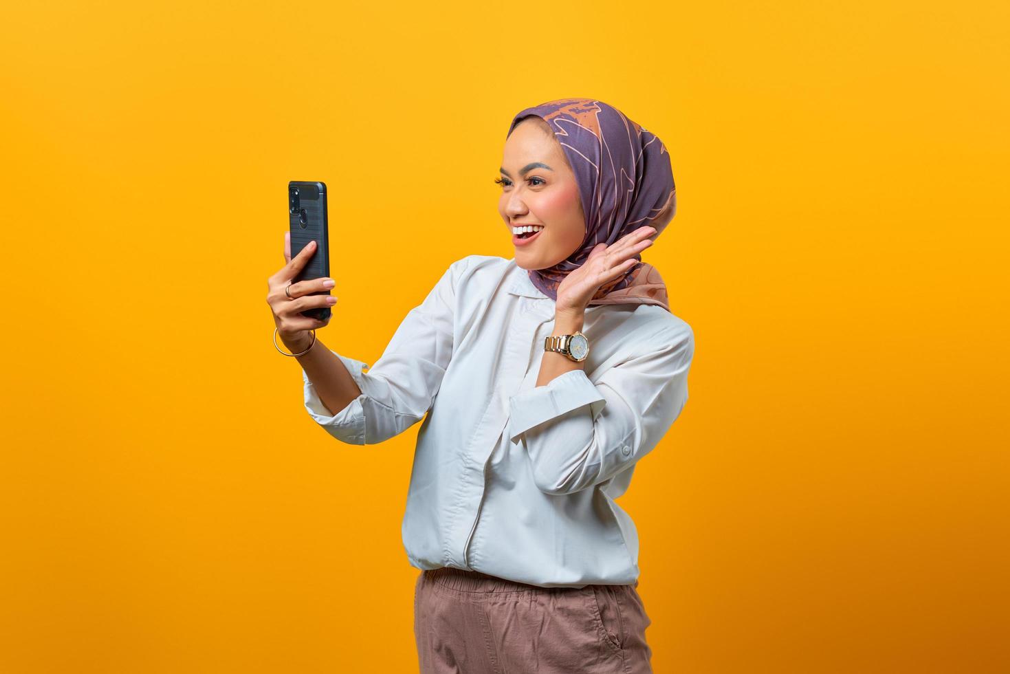 allegra donna asiatica che guarda lo smartphone con la mano alzata foto