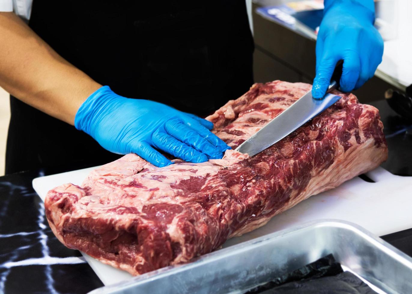 lo chef taglia la carne cruda con un coltello su una tavola, il cuoco taglia la carne cruda foto