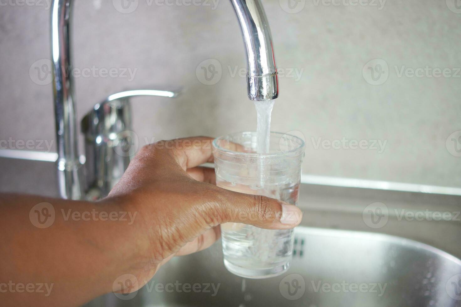 acqua scrosciante a partire dal un' rubinetto rubinetto nel un' bicchiere, potabile puro acqua concetto foto