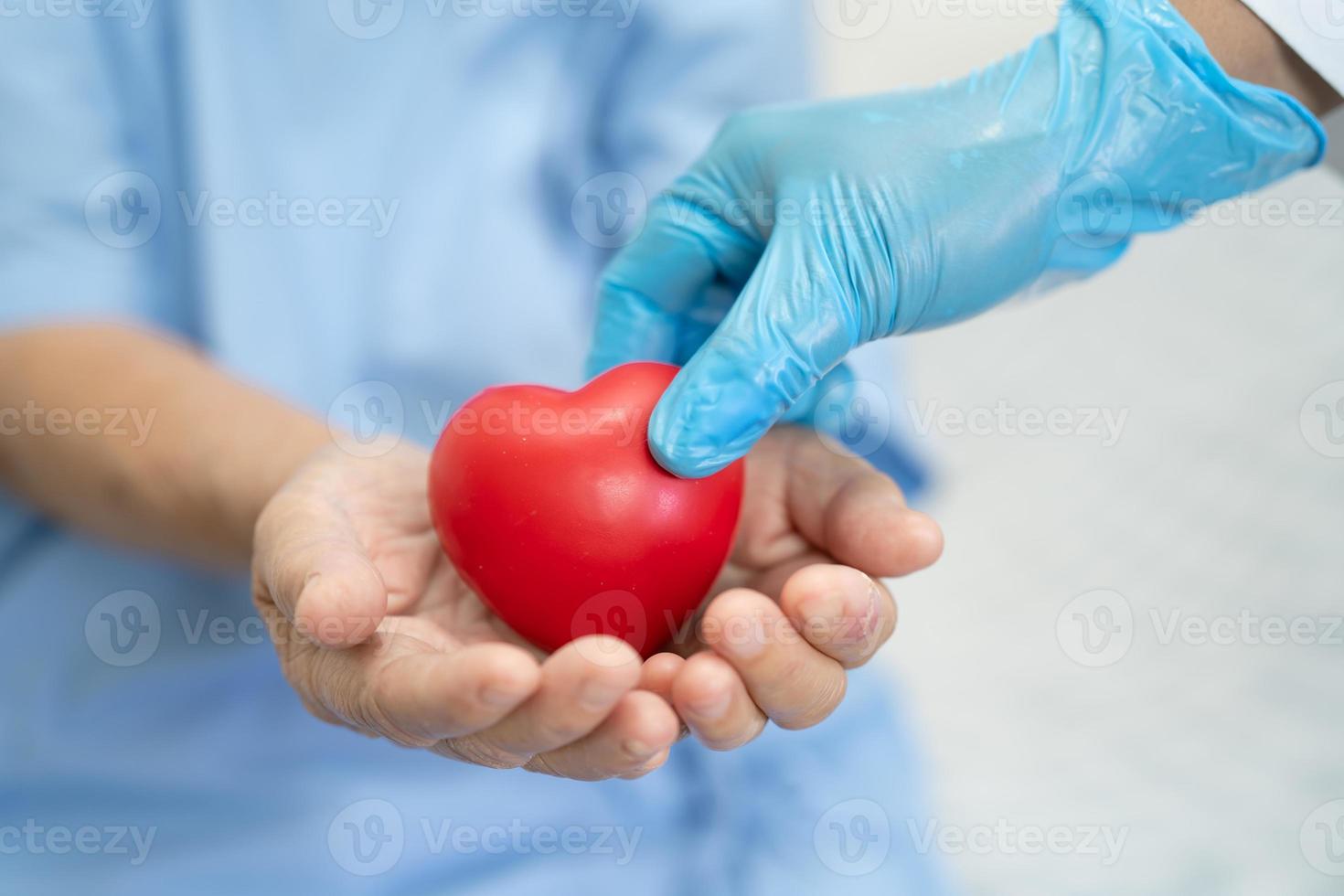 il dottore dà un cuore rosso a una paziente asiatica anziana foto