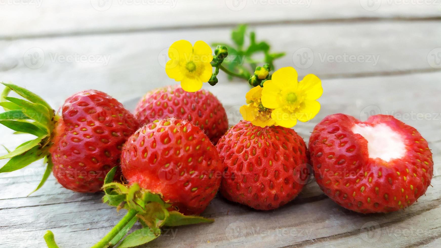 primo piano della fragola del giardino. le bacche rosse giacciono su uno sfondo di legno foto