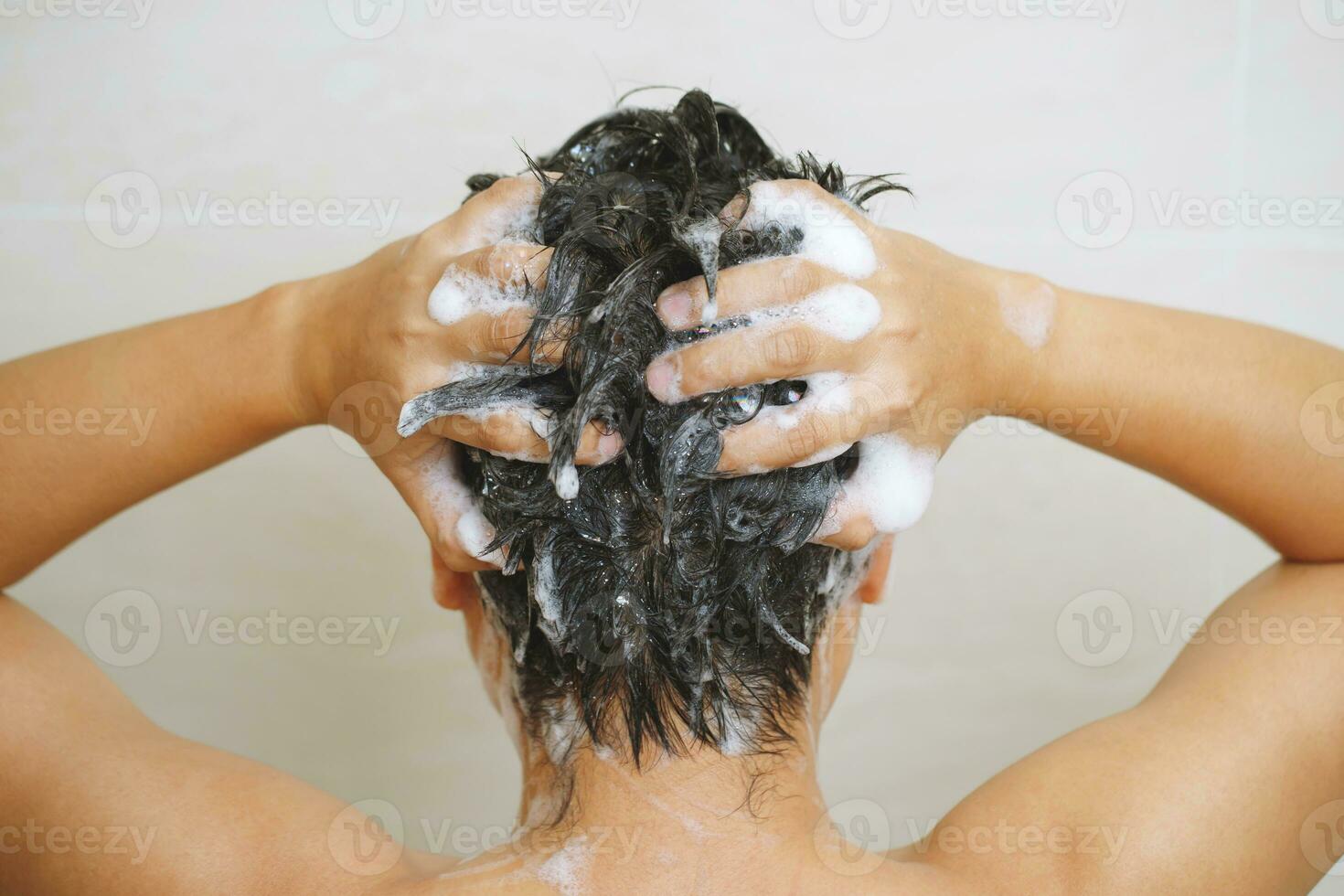 un' uomo è lavaggio il suo capelli con shampoo foto