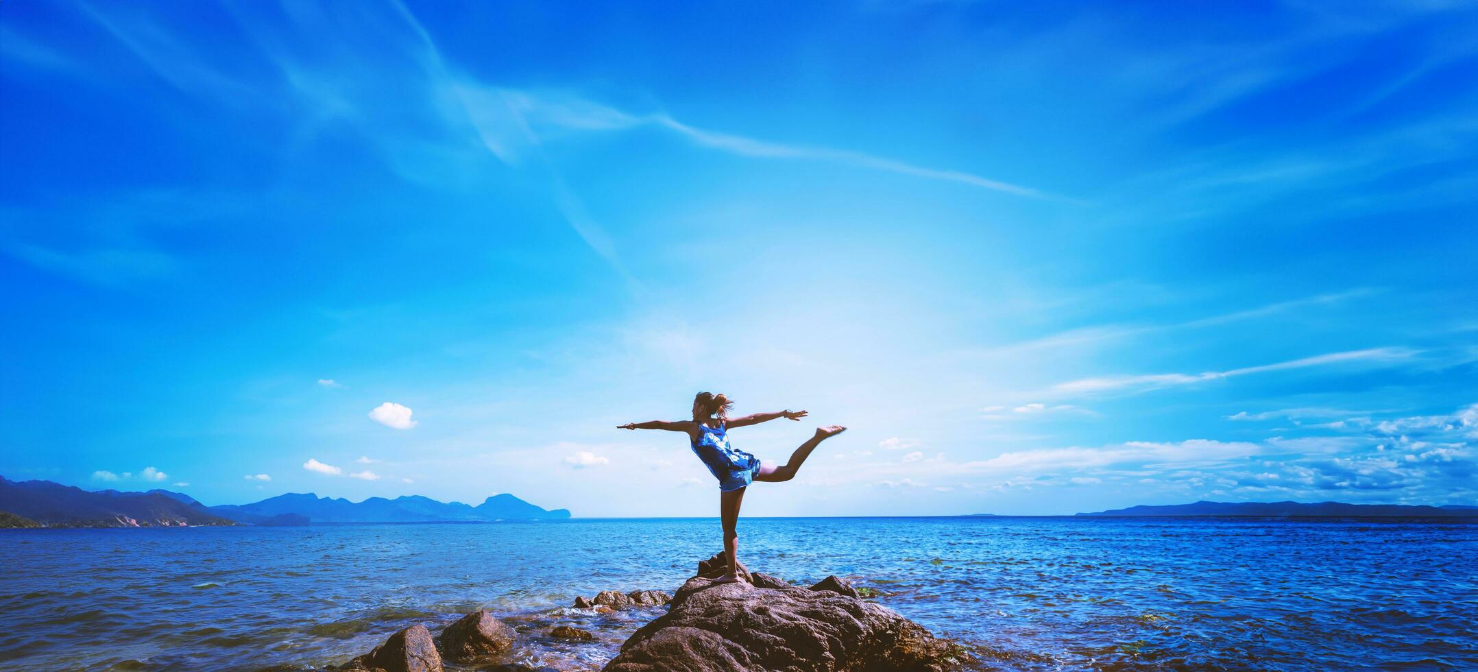 le donne asiatiche si rilassano durante le vacanze. viaggiare rilassati. gioca se lo yoga. sugli scogli in riva al mare. in estate. Tailandia foto