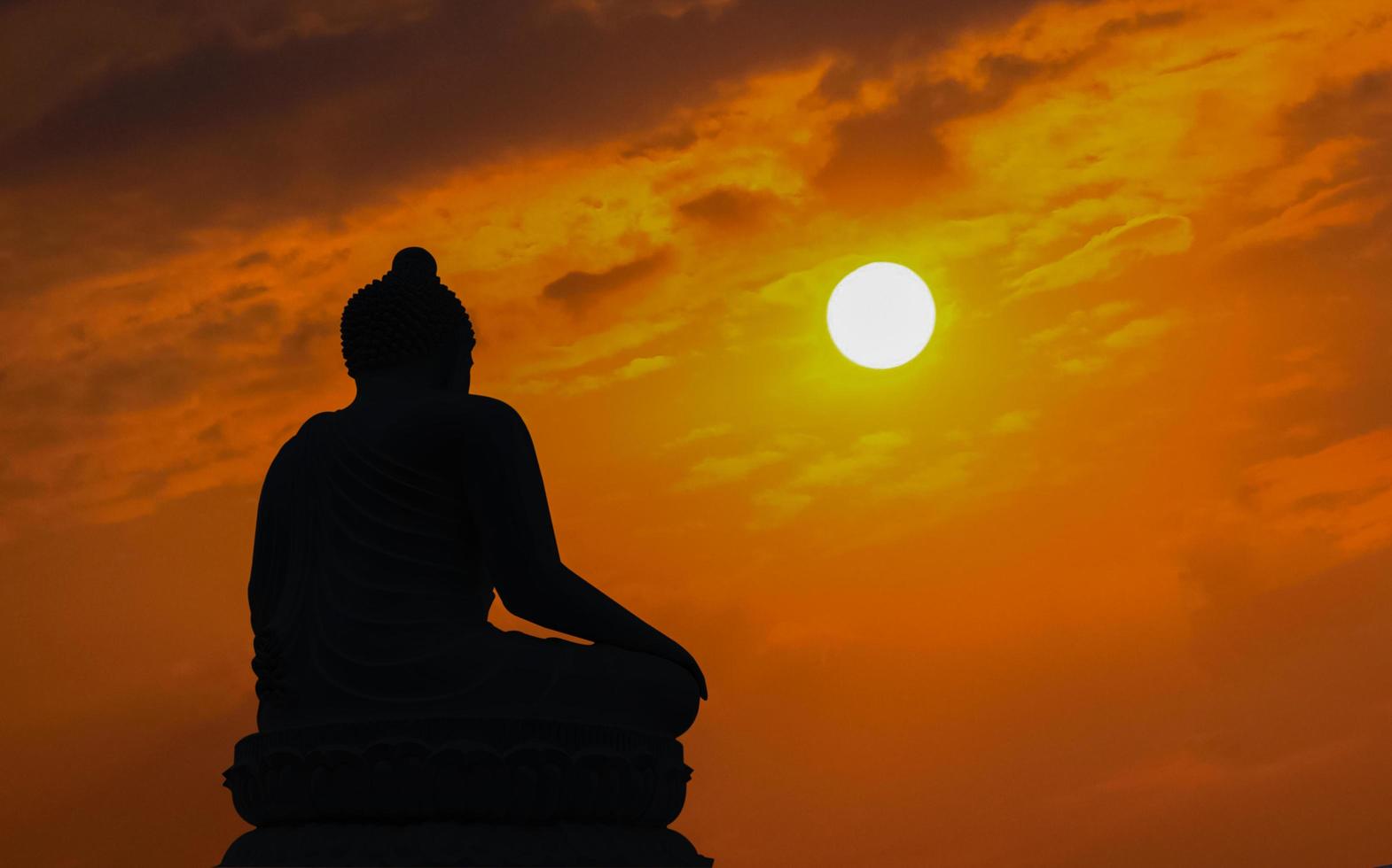 sagoma buddha sullo sfondo del tramonto che splende da dietro foto