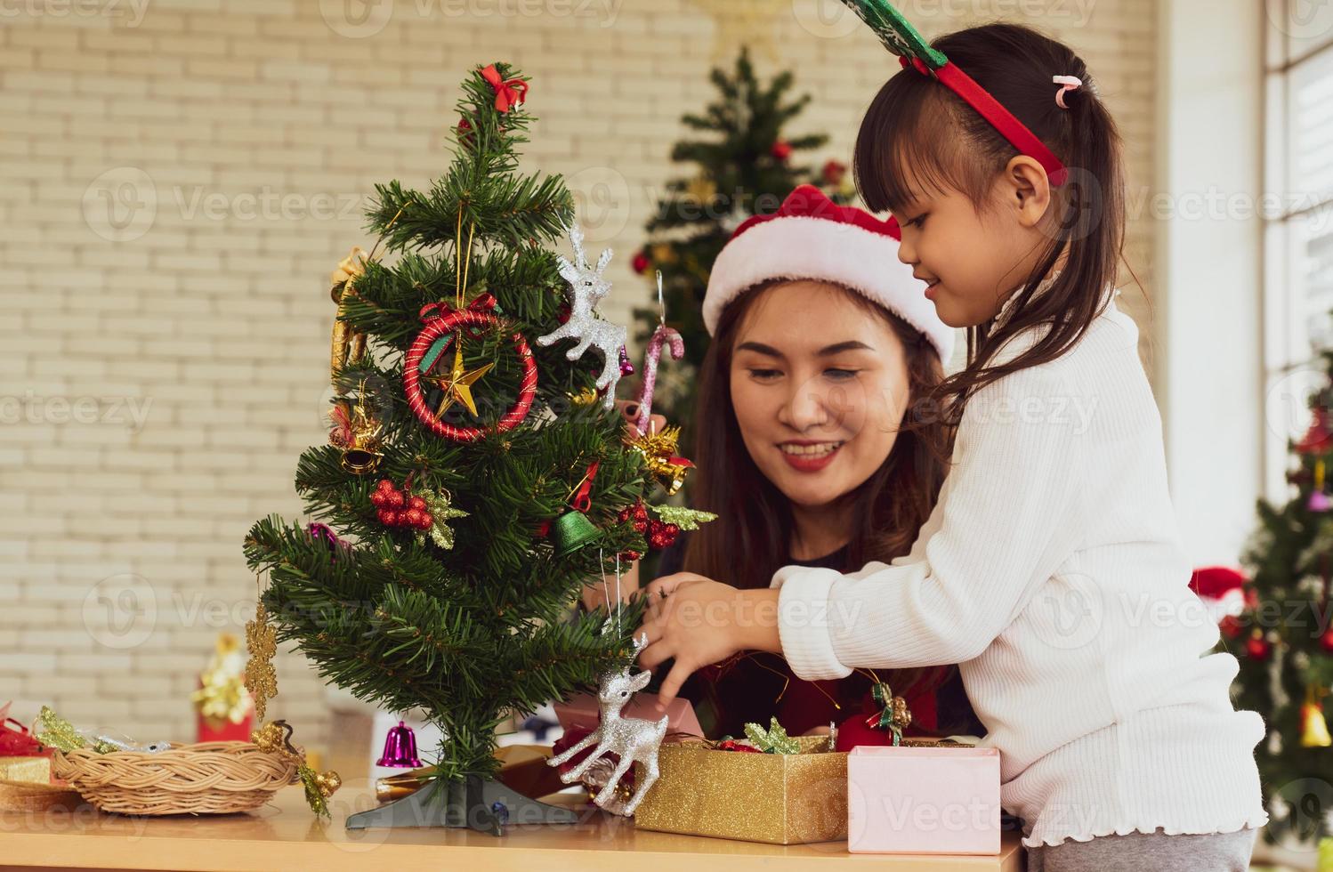 madre e figlio asiatici decorano insieme l'albero di Natale foto