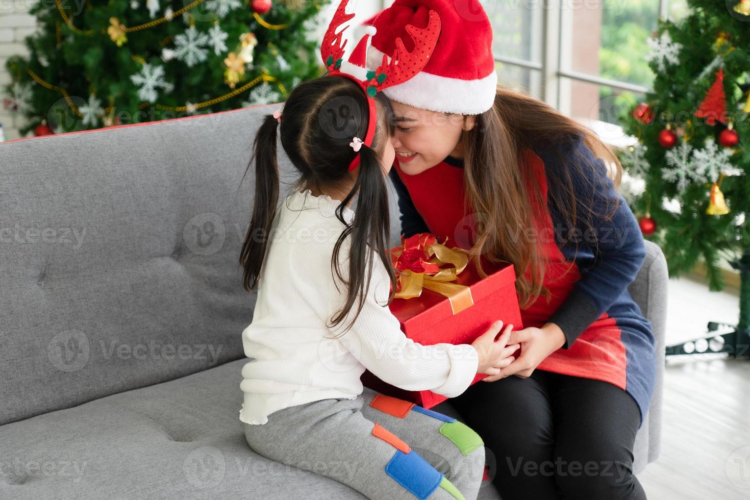 la madre asiatica e il bambino aprono insieme la scatola del regalo di natale foto