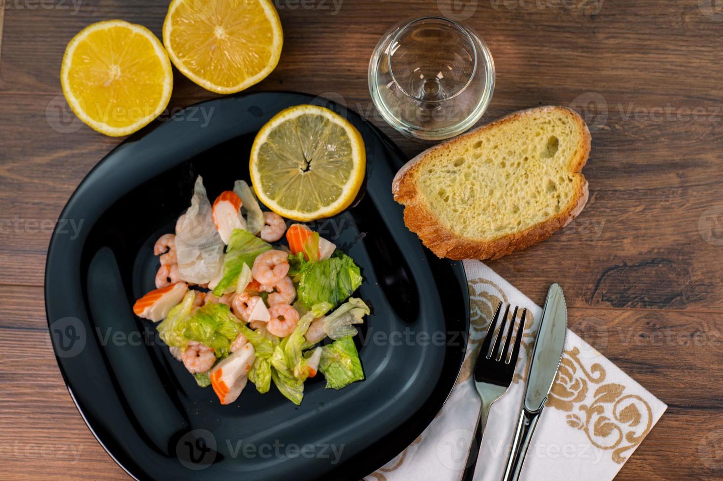 composizione di un piatto nero con gamberi e insalata di surimi foto