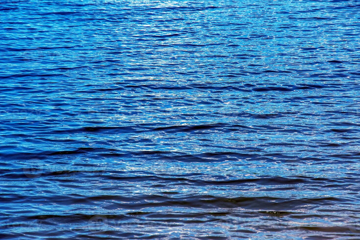 acqua ondulazione struttura sfondo. ondulato acqua superficie durante tramonto, d'oro leggero riflettendo nel il acqua. foto