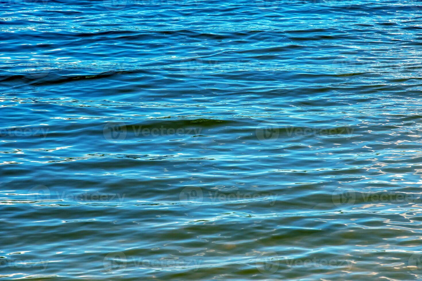 acqua ondulazione struttura sfondo. ondulato acqua superficie durante tramonto, d'oro leggero riflettendo nel il acqua. foto