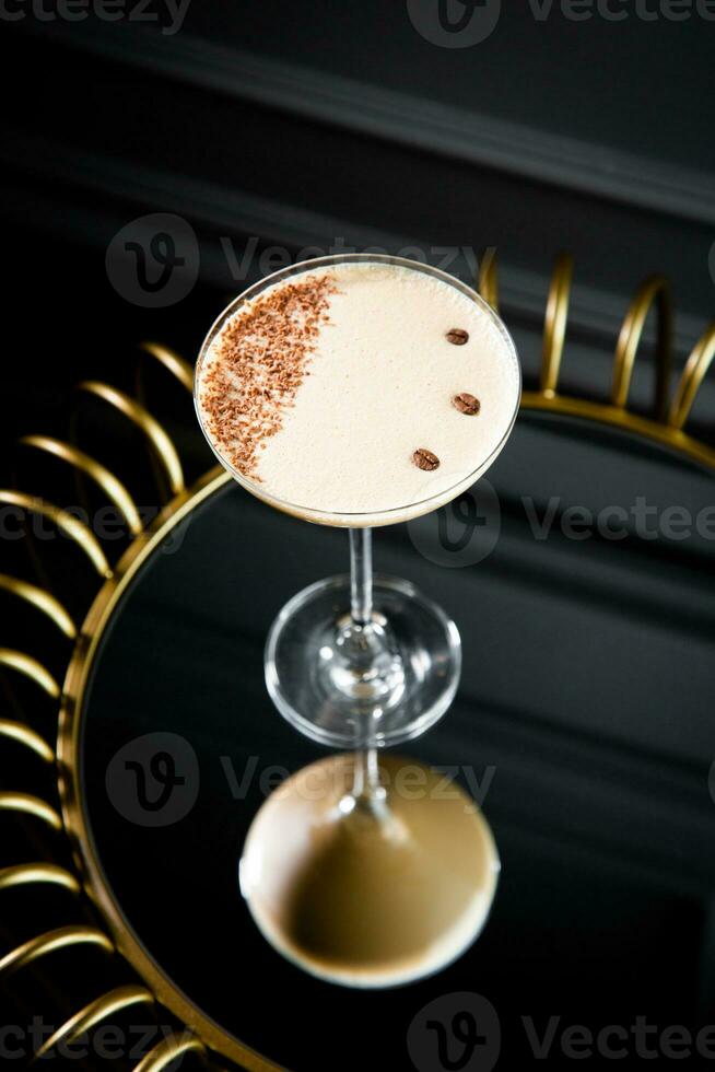 ghiacciato latte macchiato con schiuma nel un' Martini bicchiere su un' buio sfondo foto