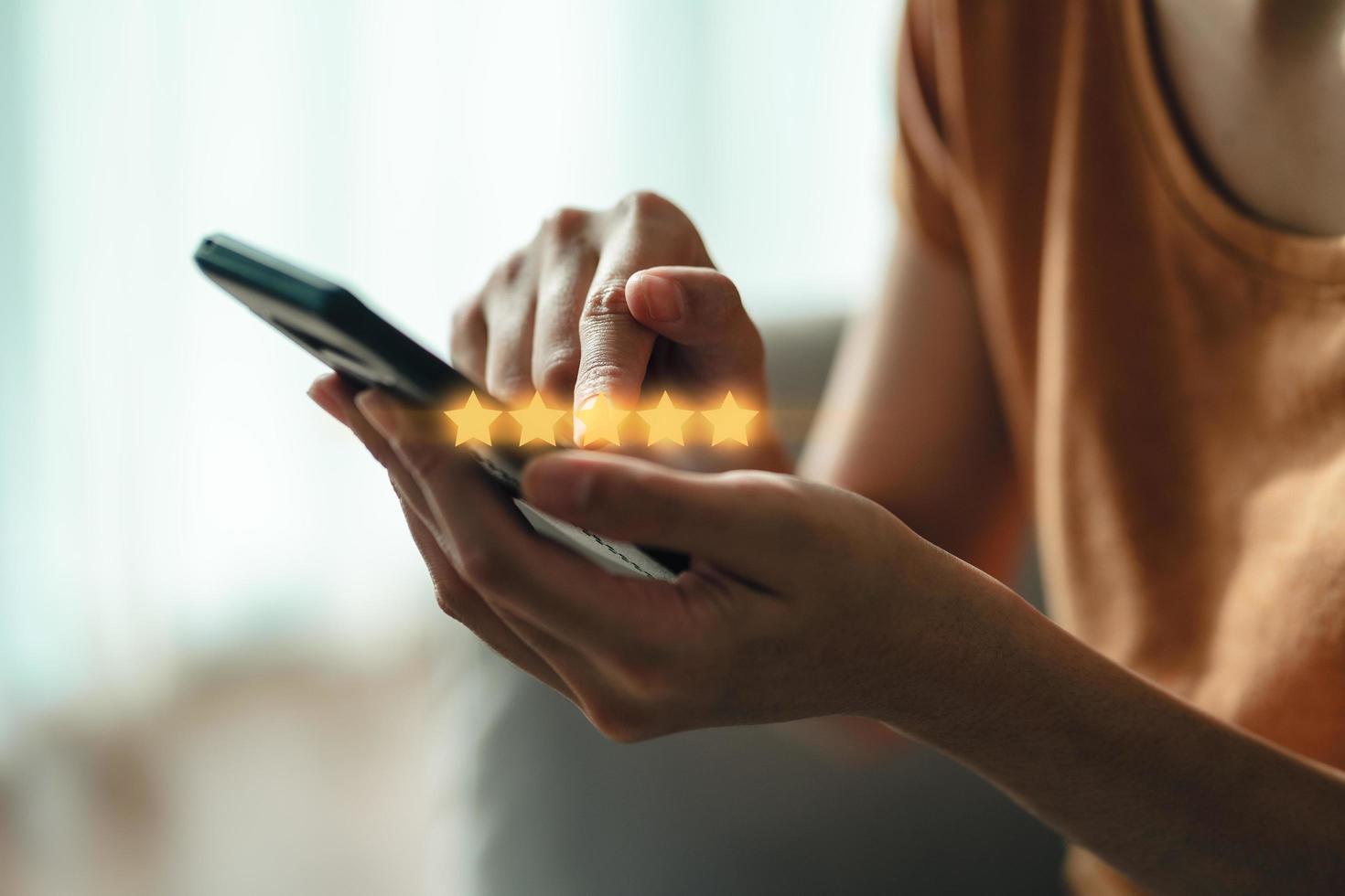 cliente donna che dà una valutazione a cinque stelle sullo smartphone foto