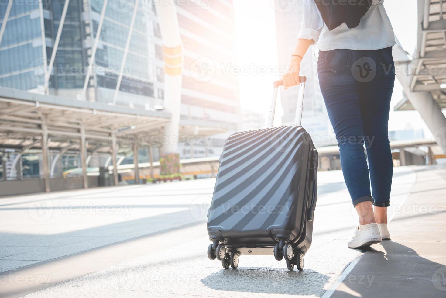 Turista viaggiatrice che cammina con i bagagli alla stazione terminale foto
