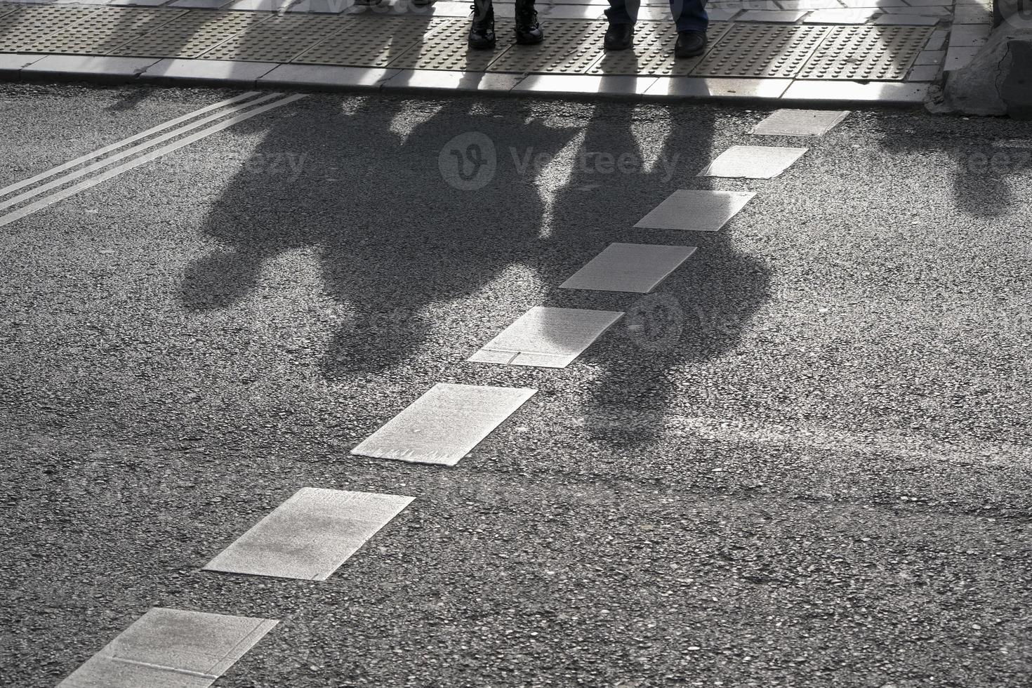 le ombre delle persone che aspettano al passaggio pedonale foto