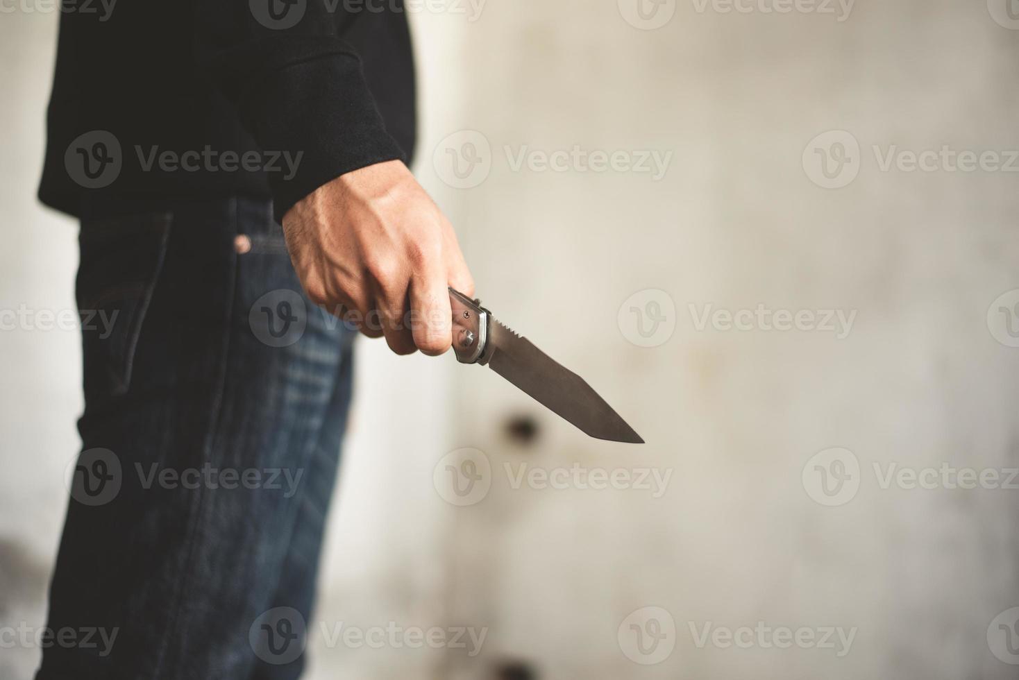 primo piano di un uomo che tiene in mano un coltello in una casa abbandonata foto