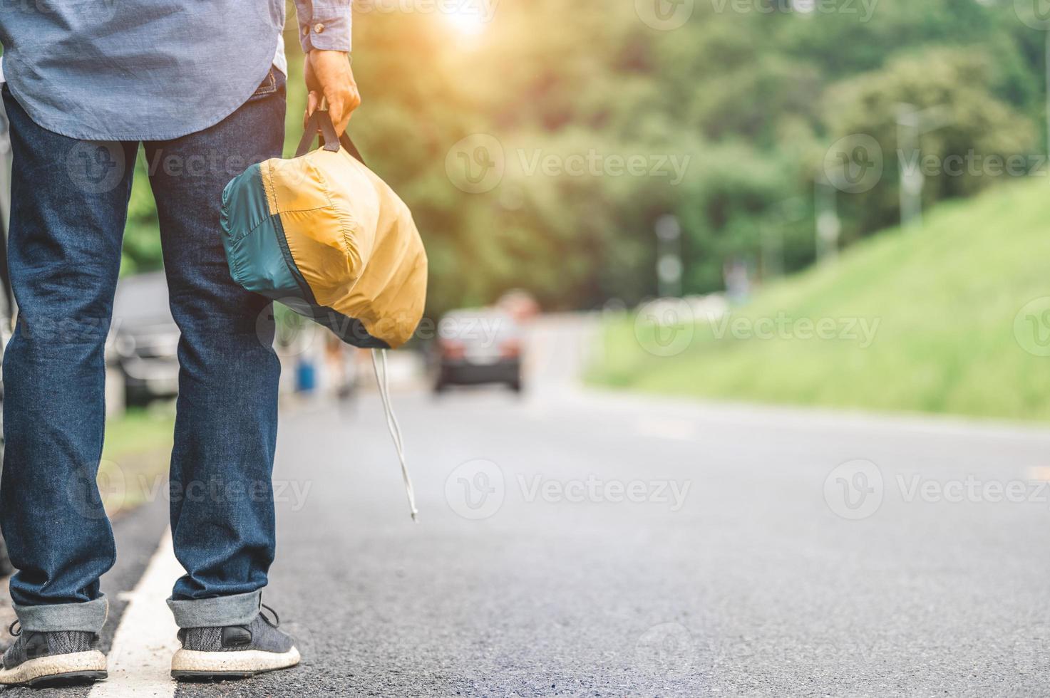 primo piano delle gambe turistiche che camminano lungo la strada con la borsa durante il viaggio foto