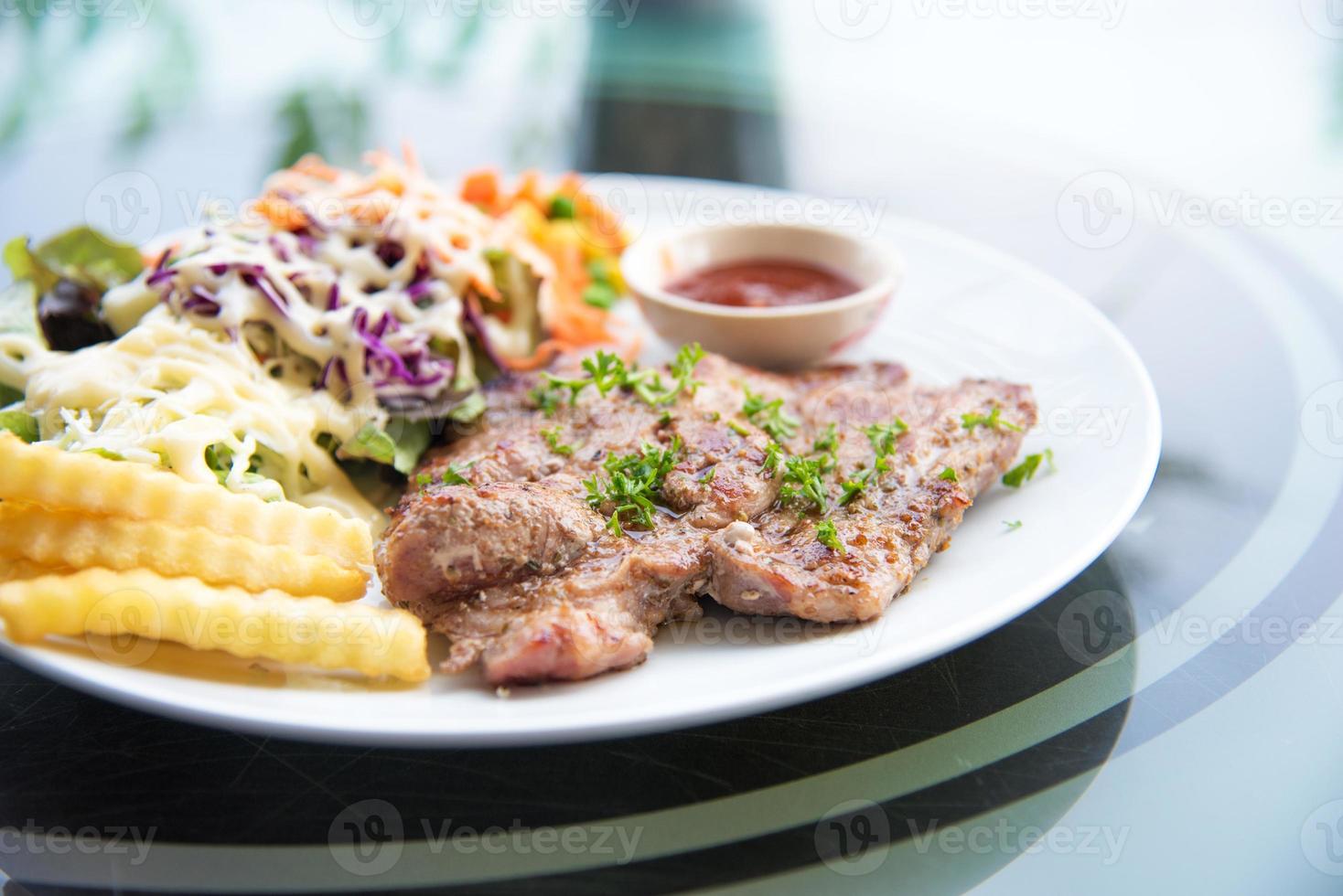 bistecca di braciola di maiale con insalata e salsa di sugo nel piatto foto