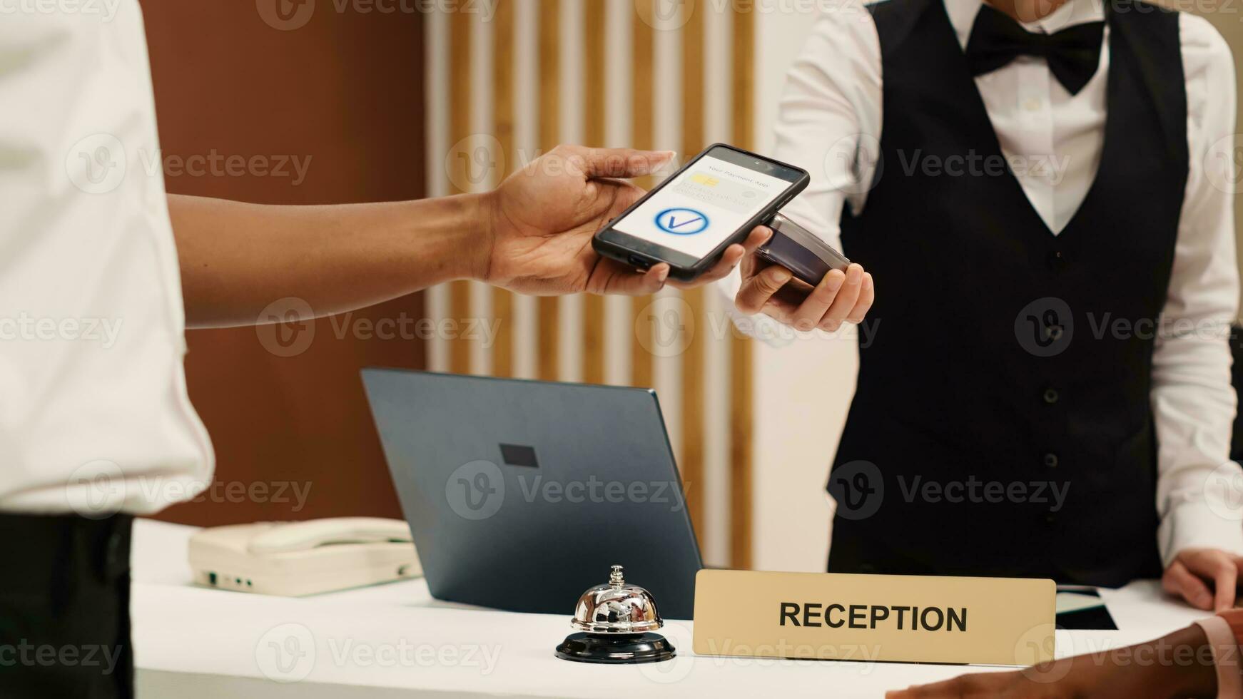 addetto alla reception utilizzando pos pagamento terminale per convalidare carta Acquista di camera Servizi e addizionale servizi, vicino su. africano americano ospite utilizzando smartphone bancario App durante dai un'occhiata nel processi foto