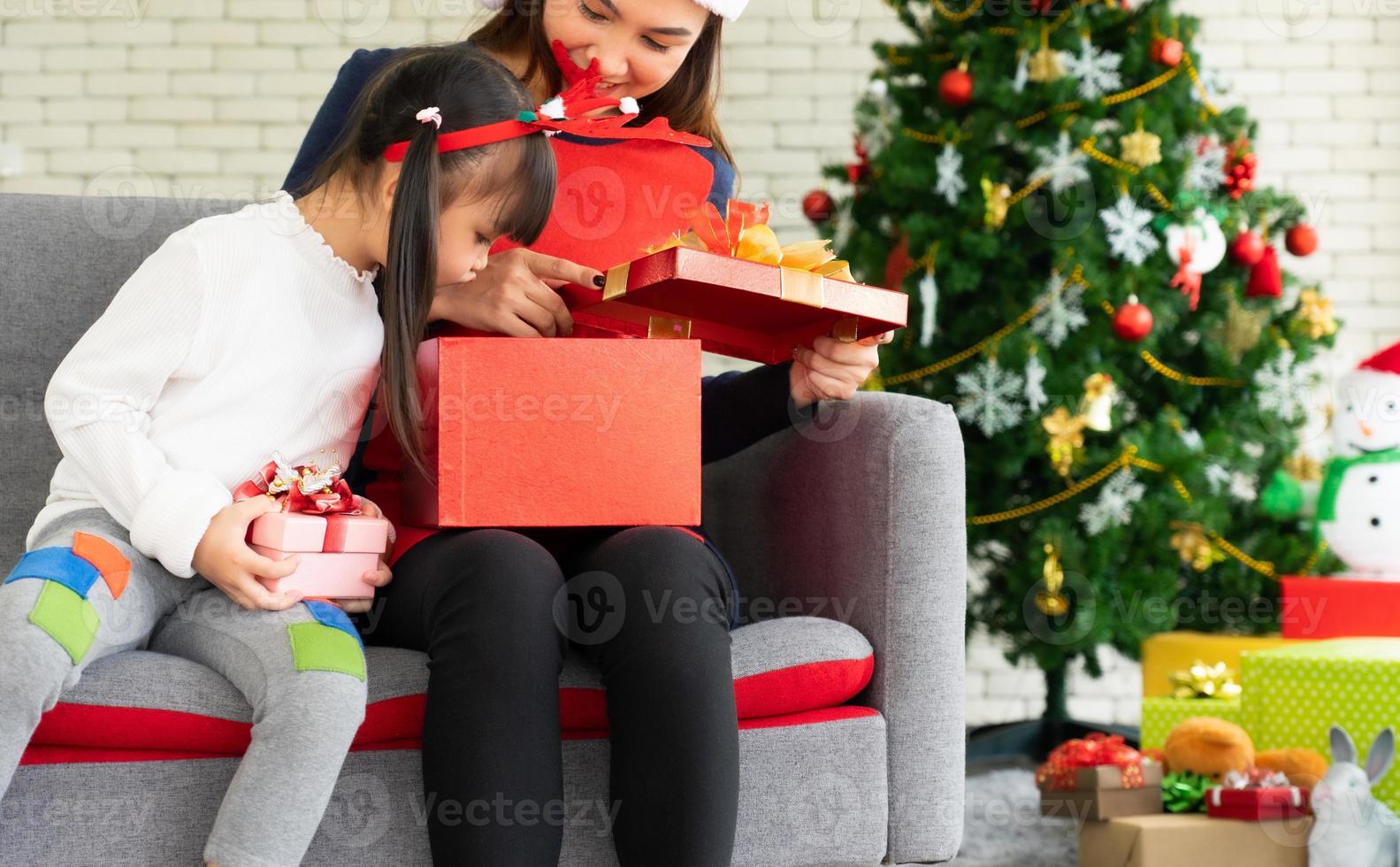 la madre asiatica e il bambino aprono insieme la scatola del regalo di natale foto