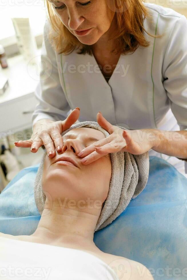 bellissimo giovane donna ricevente facciale massaggio con chiuso occhi nel un' terme salone foto